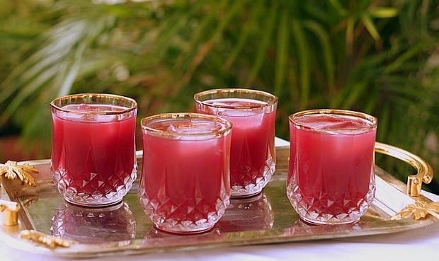 Bardak içinde servis edilmiş, üzerinde frambuaz taneleri ve nane yaprağı olan pembe renkli frambuazlı ve baharatlı şerbet