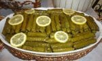 Limon dilimleri ve yeşil asma yapraklarıyla dolu, taze pişmiş Zeytinyağlı Yaprak Sarma tabağı