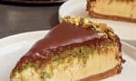 Dilimlenmiş Antep fıstıklı ve kadayıflı Dubai usulü cheesecake tabağı, üzerinde çikolata sosu gezdirilmiş.