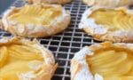 Dilimlenmiş elmalar ve badem serpilmiş, kenarları pudra şekerli elmalı pasta
