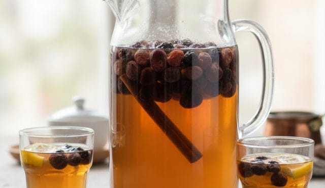 Şık bir cam kasede sunulan, içerisinde tane tane kuru üzümlerin bulunduğu, çubuk tarçın ve karanfil ile aromalandırılmış soğuk üzüm kompostosu.