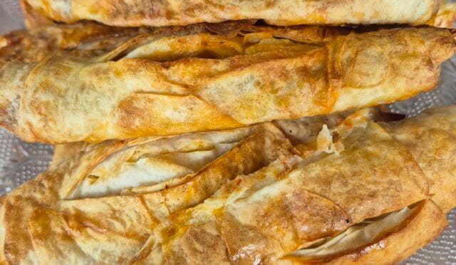 Dilimlenmiş, üzeri kızarmış, bol baharatlı ve salçalı kıymalı börek tepsisi