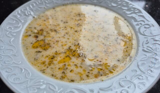 Üzerine nane ve pul biberli tereyağ gezdirilmiş, arpa şehriyeli ayran çorbası servis tabağında