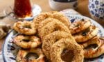 Üzeri bol susamlı ve çörek otlu, halka şeklinde pişmiş çıtır kandil simitleri fırın tepsisinde dizili halde