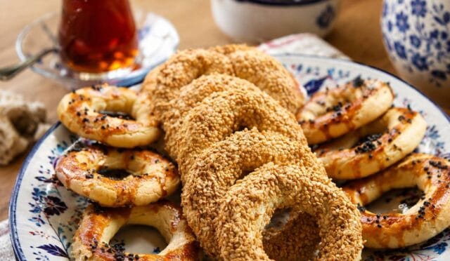 Üzeri bol susamlı ve çörek otlu, halka şeklinde pişmiş çıtır kandil simitleri fırın tepsisinde dizili halde