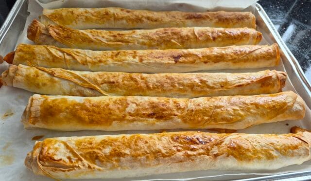 Dilimlenmiş, fırından yeni çıkmış, altın sarısı renginde, iştah açıcı patatesli börek tepsisi