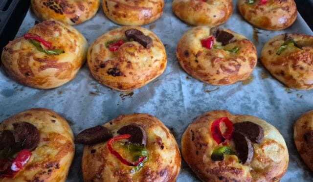 Fırından yeni çıkmış, üzeri sucuklu, biberli ve kaşarlı küçük ev yapımı pizzalar