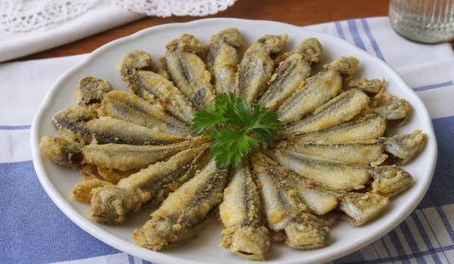 Tavada çıtır çıtır pişmiş istavrit balıkları yanında limon ve yeşilliklerle