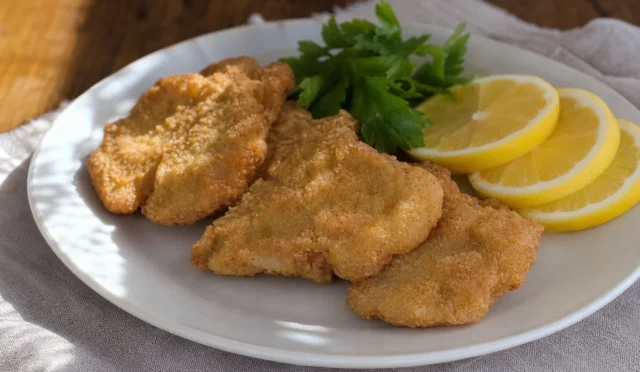 Kızarmış çıtır İstiridye Mantar Şinitzel tabakta limon ve yeşilliklerle