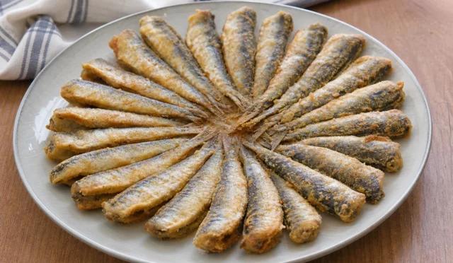 Tavada çıtır mısır unu kaplamalı sardalyalar, yanında limon ve yeşilliklerle servis edilmiş
