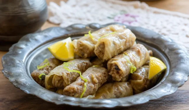 Fıstıklı üzümlü lahana sarması tabakta zeytinyağı ile servis edilmiş