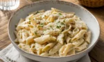 Köz patlıcanlı, kremalı sosla kaplanmış penne makarna, üzerine rendelenmiş İzmir tulum peyniri ve kıyılmış maydanoz serpiştirilmiş